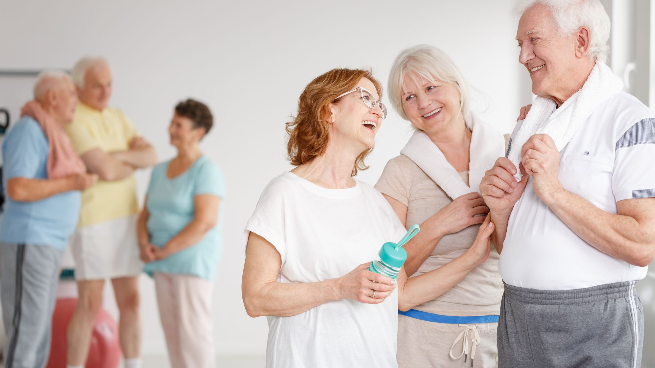 A group of happy seniors chatting and laughing after a fitness class, symbolizing the health benefits of staying socially connected.