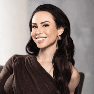 Portrait of Dr. Gabrielle Lyon smiling and seated, wearing a dark brown top with long dark hair styled in loose waves.