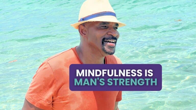 Smiling middle-aged Black man wearing a straw hat and orange shirt, standing in clear turquoise water, radiating joy and calm. (Nate Wilkins)
