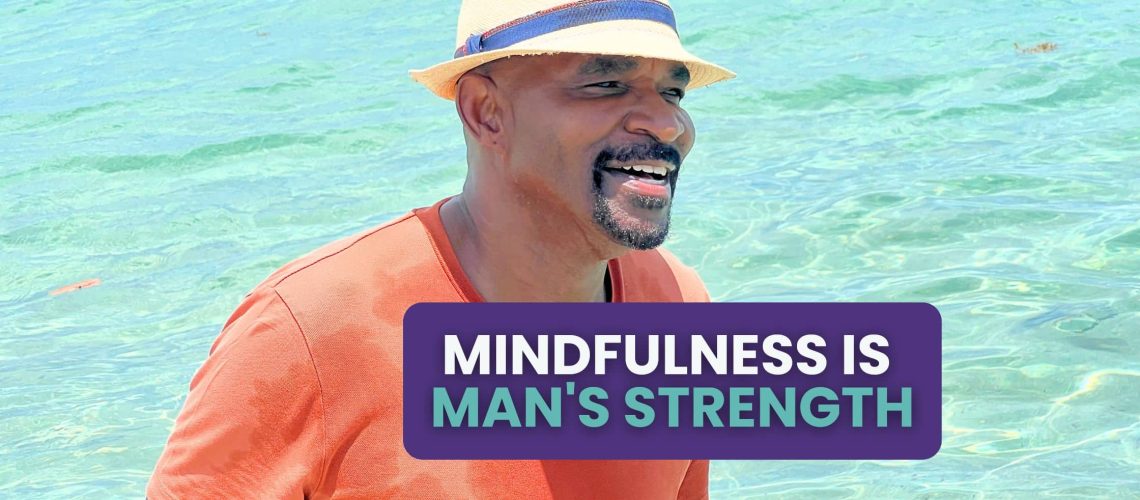 Smiling middle-aged Black man wearing a straw hat and orange shirt, standing in clear turquoise water, radiating joy and calm. (Nate Wilkins)